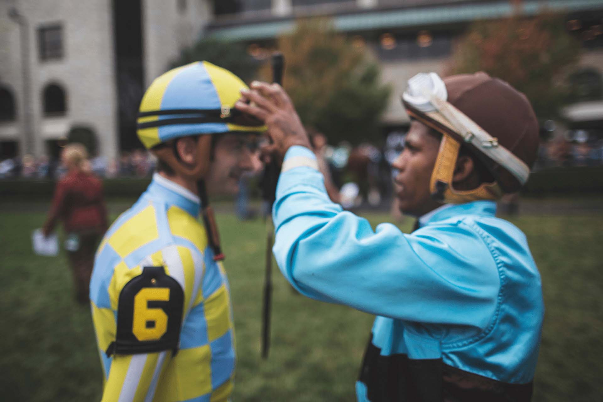 A candid photo of a jockey (right) adjusting the goggles of his fellow jockey (left).